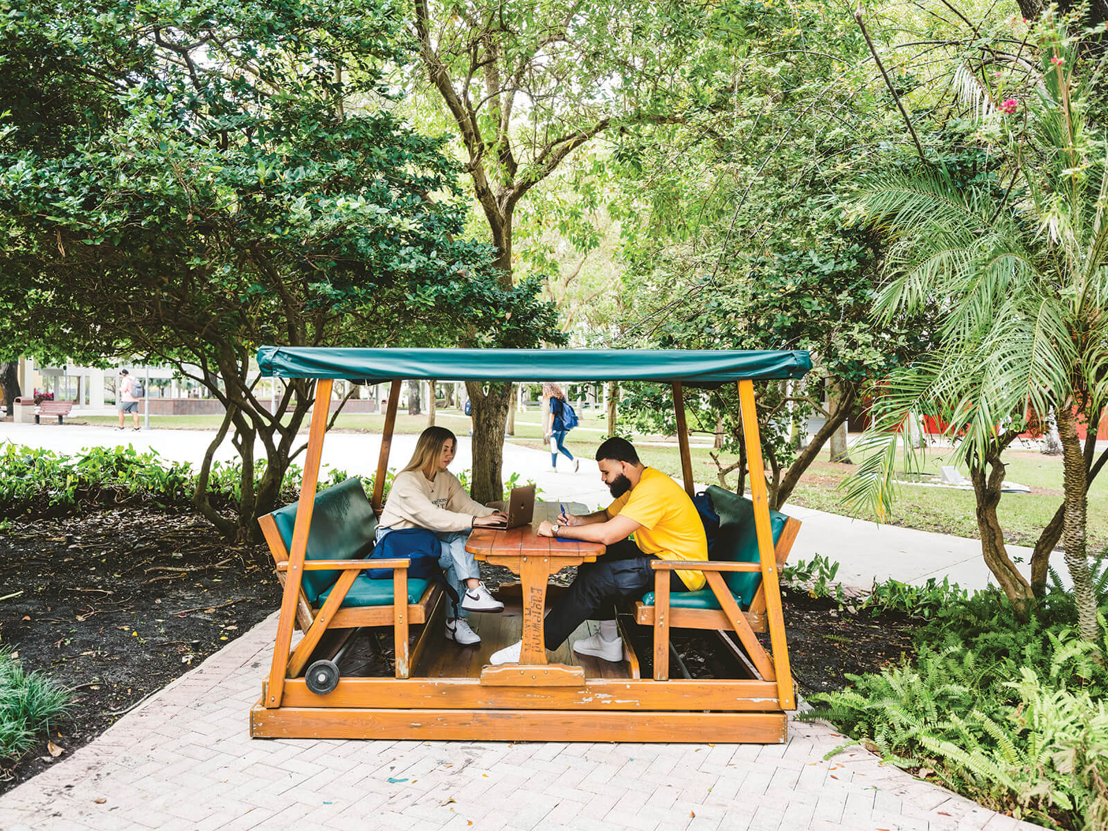 A photo of two FIU students sitting in a cabana outside of the Graham center