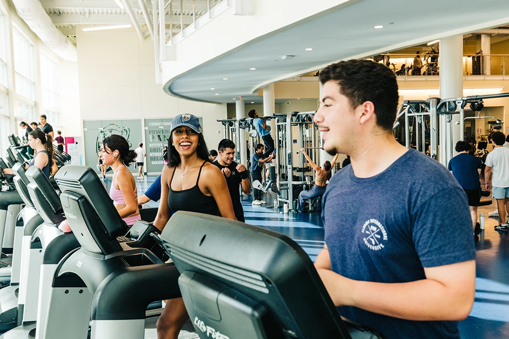 Two students talking while running on the treadmill.