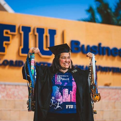 An FIU business student standing in front of the FIU Business sign