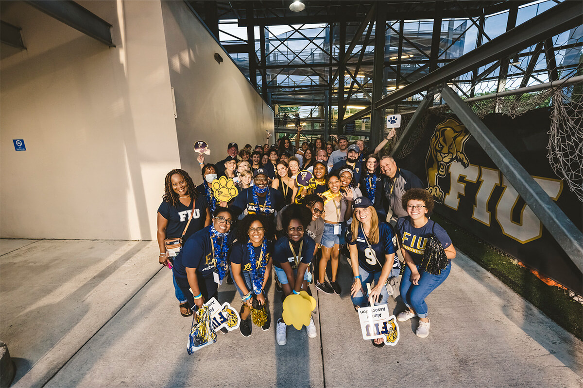 FIU students, alumni, faculty, & staff posing for a group picture while attending the FIU homecoming football game